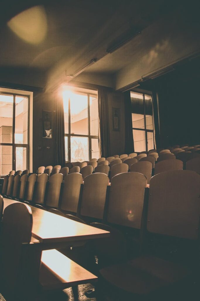 pexels photo 2201538 Sunlit auditorium with rows of empty wooden chairs and warm tones, ideal for indoor architecture themes.